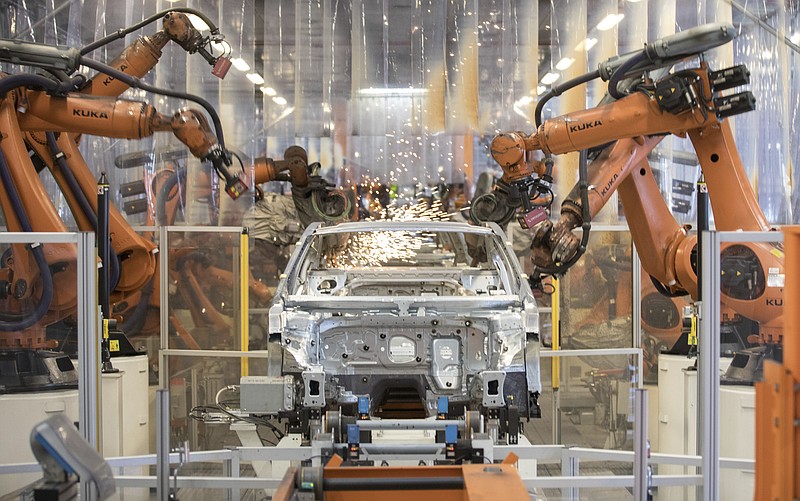 FILE -- In this Saturday, March 9, 2019 file photo robots work on a VW Passat car at a plant of the car manufacturer Volkswagen in Emden, Germany. (Joerg Sarbach/dpa via AP, file)