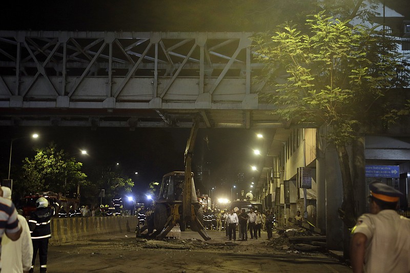 A crane works to remove a pedestrian bridge after a part of it collapsed in Mumbai, India, Thursday, March 14, 2019. A pedestrian bridge connecting a train station with a road collapsed in Mumbai on Thursday, killing at least five people and injuring more than 30, police said. (AP Photo/Rajanish Kakade)