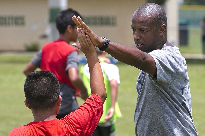 In a September 2016 photo, Yale's women's Head Soccer Coach Rudy Meredith gives a high five to a player after making a great play in a scrimmage, in Frankfort, Ky. According to the federal indictments unsealed Tuesday, March 12, 2019, Meredith put a prospective student who didn’t play soccer on a school list of recruits, doctored her supporting portfolio to indicate she was a player, and later accepted $400,000 from the head of a college placement company.  (Doug Engle/Star-Banner via AP)