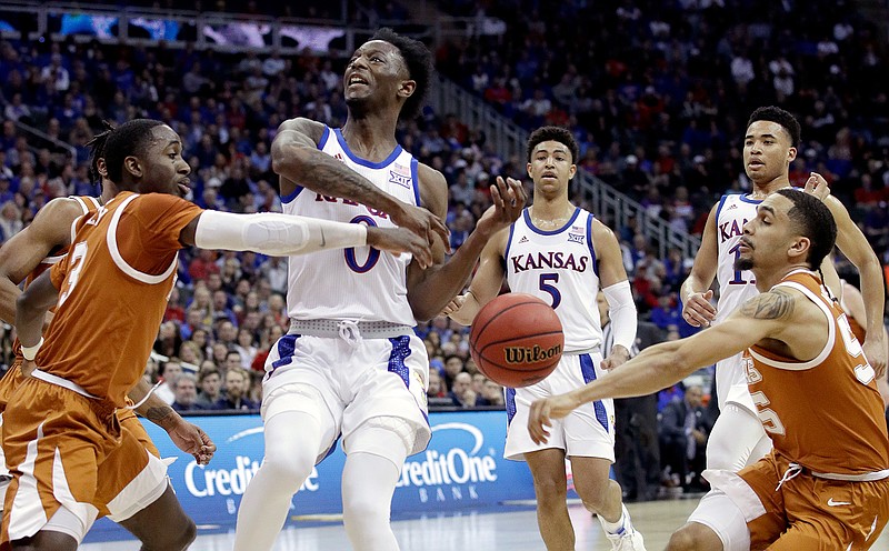 Texas' Courtney Ramey, left, and Kamaka Hepa, right, strip the ball from Kansas' Marcus Garrett (0) during the first half of an NCAA college basketball game in the Big 12 men's tournament Thursday, March 14, 2019, in Kansas City, Mo. (AP Photo/Charlie Riedel)