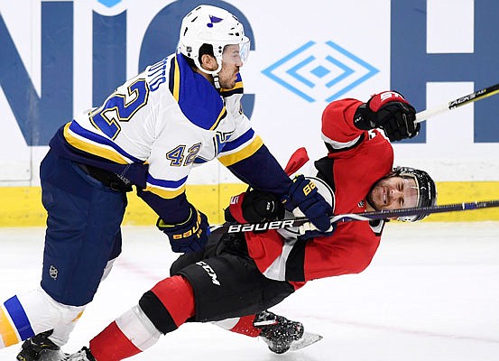 Brian Gibbons of the Senators falls under the stick of Michael Del Zotto of the Blues during Thursday night's game in Ottawa, Ontario.