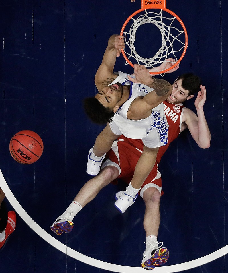 Alabama guard Riley Norris watches from the floor as Kentucky forward Nick Richards dunks the ball above him in the first half of an NCAA college basketball game at the Southeastern Conference tournament Friday, March 15, 2019, in Nashville, Tenn. (AP Photo/Mark Humphrey)