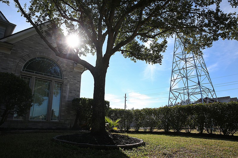 In this Dec. 11, 2018 photo, a CenterPoint Energy electricity tower, which was put up the past summer, stands outside of Eboni Hollier's house in Pearland, Texas.  Two proposed bills could give Texas landowners more options should electric transmission towers be put up on or near their property.  (Yi-Chin Lee/Houston Chronicle via AP)