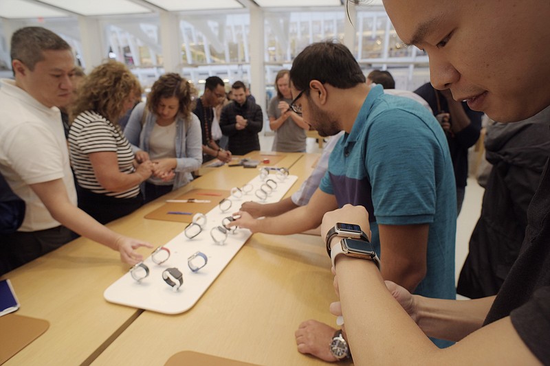 FILE- In this Sept. 21, 2018 file photo customers look at Apple Watches at an Apple store in New York. A huge study suggests the Apple Watch sometimes can detect a worrisome irregular heartbeat. But experts say more work is needed to tell if using wearable technology to screen for heart problems really helps.  (AP Photo/Patrick Sison, File)