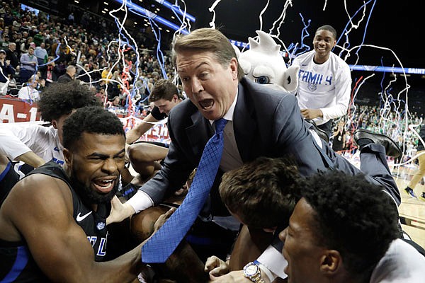 Saint Louis coach Travis Ford leaps onto the pile of his players during a celebration Sunday after the Billikens defeated St. Bonaventure 55-53 in the title game of the Atlantic 10 Tournament in New York.