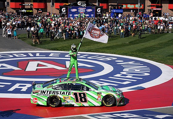 Kyle Busch stands on his car after winning the NASCAR Cup Series race Sunday at Auto Club Speedway in Fontana, Calif.