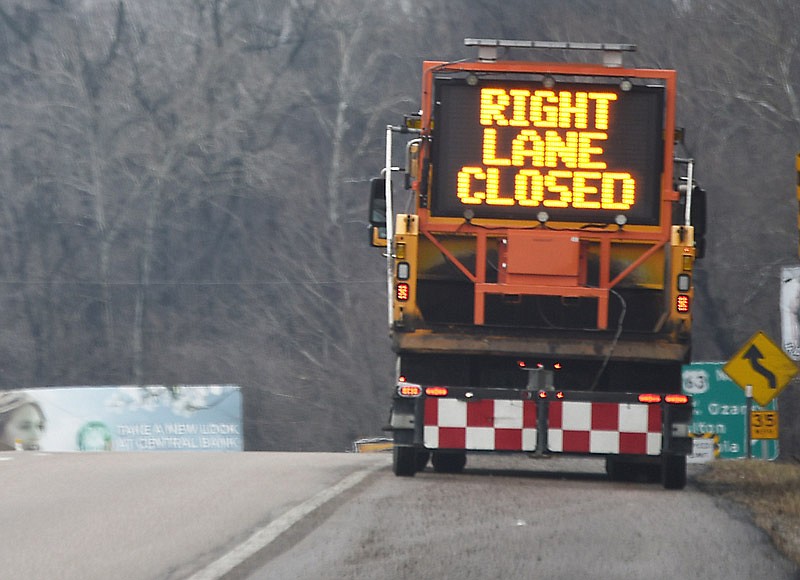 In this Feb. 22, 2018 file photo, a sign on a Missouri Department of Transportation truck asks motorists to move into the left lane to avoid MoDOT employees as they shovel asphalt mix into potholes along U.S. 50 in Jefferson City.