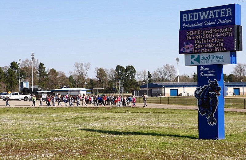 Redwater Elementary students are escorted to the parking lot to be picked up by parents because of a bomb threat on Tuesday, March 19, 2019, in Redwater, Texas. 