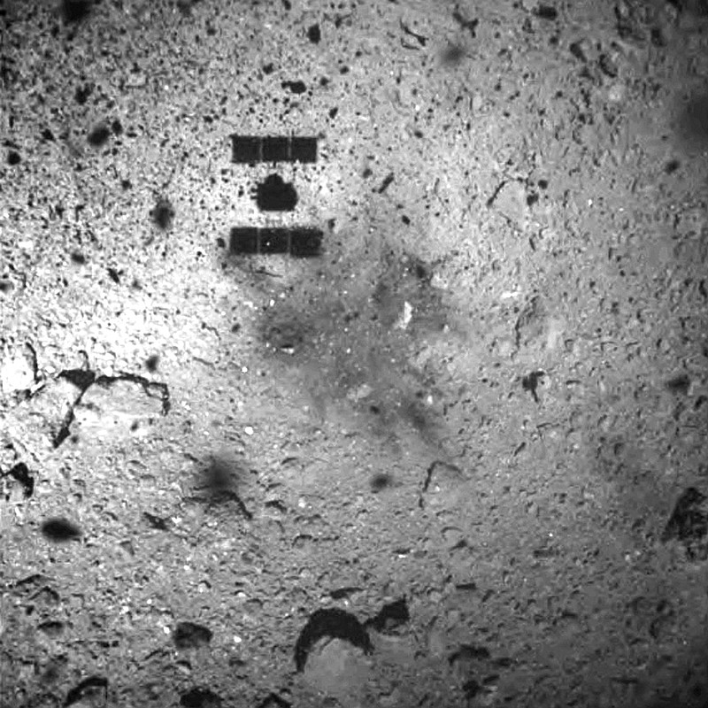  In this Feb. 22, 2019, file photo, this image released by the Japan Aerospace Exploration Agency (JAXA) shows the shadow, center above, of the Hayabusa2 spacecraft after its successful touchdown on the asteroid Ryugu.  Japan's space agency says its Hayabusa2 spacecraft will follow up last month's touchdown on a distant asteroid with another risky mission — to drop an explosive to make a crater and collect underground samples to get possible clues to the origin of the solar system. (JAXA via AP, File)
