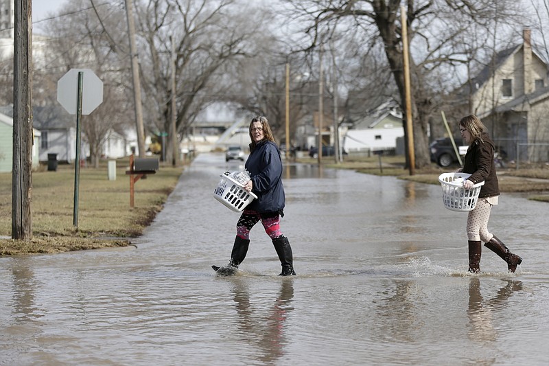 Akashi Haynes, left, and her daughter Tabitha Viers carry their belongings rescued from their flooded home in Fremont, Neb., Monday, March 18, 2019. Authorities say flooding from the Platte River and other waterways is so bad that just one highway lane into Fremont remains uncovered, and access to that road is severely restricted. (AP Photo/Nati Harnik)