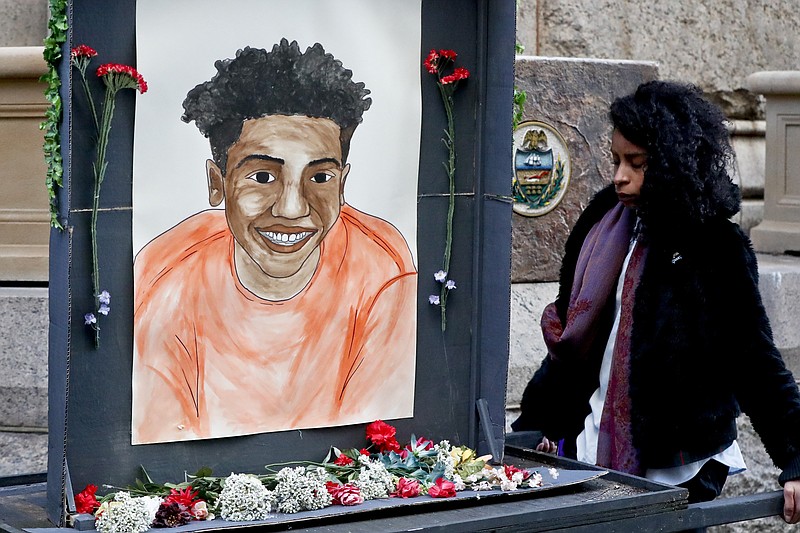 A woman who did not want to be identified holds a memorial display with a drawing of Antwon Rose II in front of the court house on the first day of the trial for Michael Rosfeld, a former police officer in East Pittsburgh, Pa., begins on Tuesday, March 19, 2019, in Pittsburgh. Rosfeld is charged with criminal homicide in the fatal shooting of Antwon Rose II as he fled during a traffic stop on June 19, 2018. (AP Photo/Keith Srakocic)