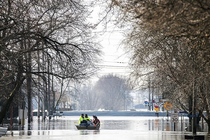 People on a boat float down floodwaters that cover Washington Street Wednesday, March 20, 2019, in Hamburg, Iowa. As some communities along the Missouri River start to shift their focus to flood recovery after a late-winter storm, residents in two Iowa cities are still in crisis mode because their treatment plants have shut down and they lack fresh water. (Chris Machian/Omaha World-Herald via AP)