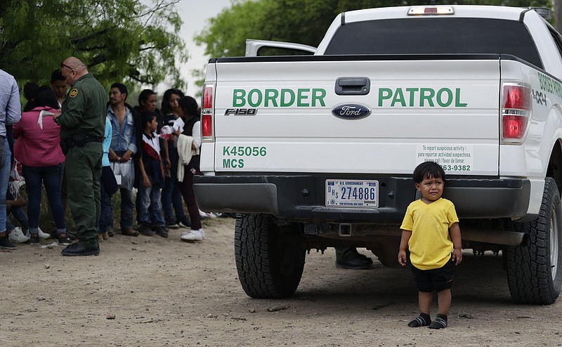 In this Thursday, March 14, 2019, photo, William Josue Gonzales Garcia, 2, who was traveling with his parents, waits with other families who crossed the nearby U.S.-Mexico border near McAllen, Texas. They are waiting for Border Patrol agents to check names and documents. Immigration authorities say they expect the ongoing surge of Central American families crossing the border to multiply in the coming months. (AP Photo/Eric Gay)