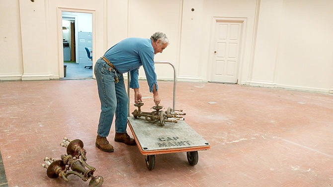 Matthew Coley, of Facilities Management, removes the last of the wall sconces from the former legislative research room on the Capitol's first floor.
