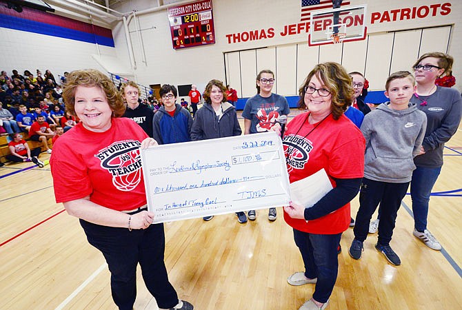 Sharman Banks and Tammy Schmitz, of Thomas Jefferson Middle School, hold an oversized check Friday from the Pennies for Patients fundraiser, which honors Tanay Goel, who has been diagnosed and is currently receiving treatment for leukemia. In the background are The Hero Squad students who raised the most money. Each year, TJMS raises money for the Leukemia & Lymphoma Society. 