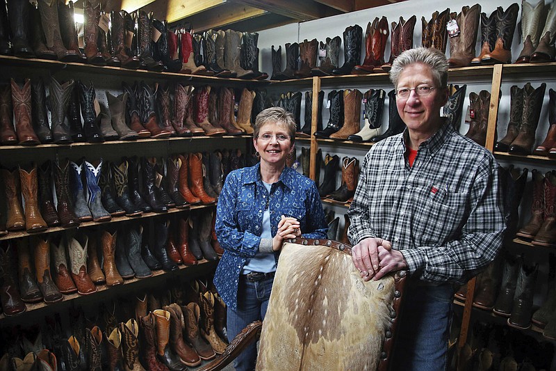 In this Wednesday, March 13, 2019 photo, Deb and Kevin Durken pose for a photo in their boot store The Boot Shack in St. Cloud, Minn. The bookkeeper for the Durken's store forged checks and stole an estimated $225,000 over 10 years, Deb says. The bookkeeper was able to keep stealing because she was trusted to do her work unsupervised. (AP Photo/Jim Mone)