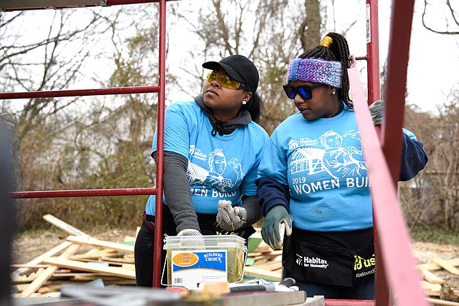 Jassmin Robinson, left, and Chloe Hill gather nails needed to install vinyl siding Saturday as they volunteer with River City Habitat for Humanity. Robinson is the owner of the house being built.