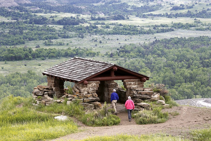 FILE--In this Wednesday, June 11, 2014, file photo, James Lyons and Florence Reaves, from Kirkwood, Mo., hike to a stone lookout over the Little Missouri River inside the Theodore Roosevelt National Park, located in the Badlands of North Dakota. Parties involved in a dispute over whether North Dakota regulators should be involved in the siting of a controversial oil refinery near Theodore Roosevelt National Park are battling in state court. The dispute is over whether state regulators should have reviewed the site of the $800 million Davis Refinery. Environmental groups say yes, but developer Meridian Energy and the state Public Service Commission are both urging a judge to rule against a hearing. (AP Photo/Charles Rex Arbogast, File)
