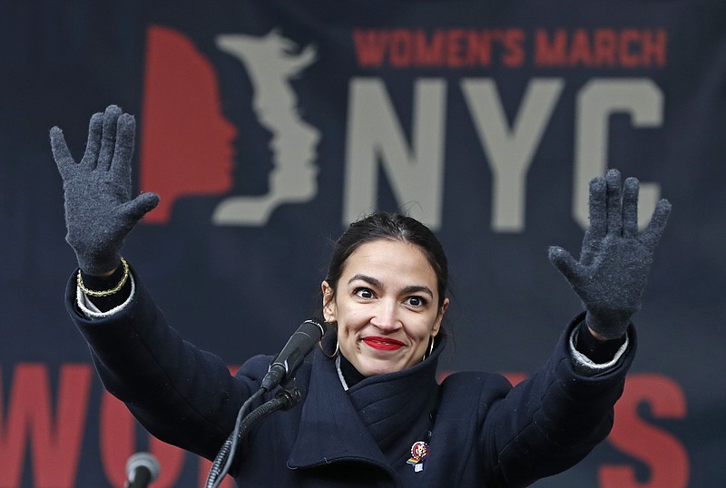FILE - In this Jan. 19, 2019, file photo, U.S. Rep. Alexandria Ocasio-Cortez, (D-New York) waves to the crowd after speaking at Women's Unity Rally in Lower Manhattan in New York. To Democratic supporters, the Green New Deal is a touchstone, a call to arms to combat climate change. To Republican opponents, it’s zealous environmentalism, a roadmap to national bankruptcy. Lost in the clamor is the reality that, if passed, the much-hyped Green New Deal would require the government to do absolutely nothing. (AP Photo/Kathy Willens, File)