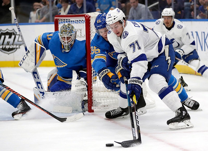 Colton Parayko of the Blues tries to poke the puck away from Anthony Cirelli of the Lightning as Blues goaltender Jordan Binnington watches in the first period of Saturday's game in St. Louis.