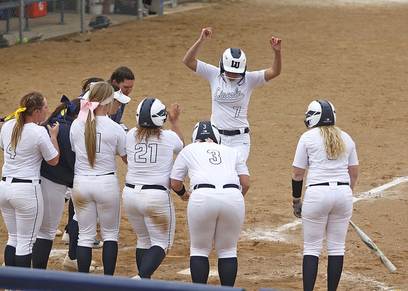 Lincoln freshman Trista Heavin (7) jumps on home plate as her teammates greet her after she hit a three-run home run during the first game of Saturday's doubleheader against Nebraska-Kearney at LU Softball Field.