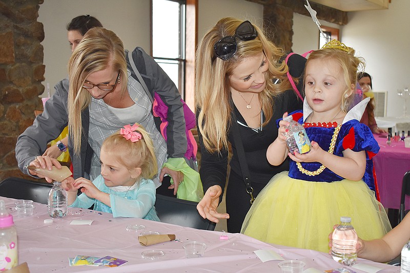 From left, Lauren Schanbacher and daughter Lucy, 5, and Kyla Asel and daughter Brooklyn, 3, make snow globes at the third annual Princess Party Sunday at McClung Park. More than 100 girls came to make crafts, eat, dance and interact with older princesses. They were also able to have their hair styled and make up done.