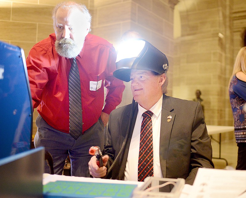 Welding instructor Charlie Grosvenor shows Rep. Tim Remole his percentage of accuracy Wednesday after Remole used a virtual welding machine to test his skills during Corrections Day at the Capitol. The program helps those who are incarcerated learn the basics while receiving curriculum for welding and safety that will help them become certified welders.