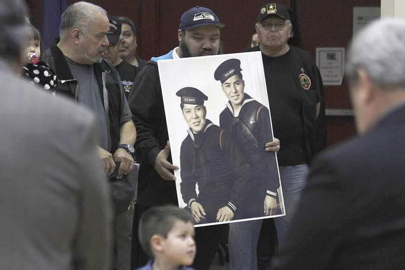 In this Monday, March 18, 2019 photo, family members of brothers Mark Jacobs Jr. and Harvey Jacobs observe a moment of silence during a ceremony honoring Tlingit code talkers in Juneau, Alaska. Five long-deceased Alaska Native servicemen are being hailed by the state of Alaska for their life-saving efforts during World War II. Alaska lawmakers this month passed a formal citation honoring the Tlingit men for using their Native language to help the military outsmart the Japanese with codes they could not break. (Alex McCarthy/The Juneau Empire via AP)