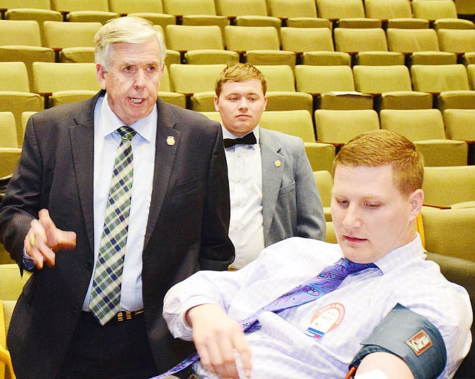 Gov. Mike Parson encourages his Communications Director Steele Shippy on Wednesday while donating blood during a Red Cross blood drive at the Harry S Truman State Office Building. The governor didn't donate over concerns of a recent surgery. Shippy said he is a regular donor.