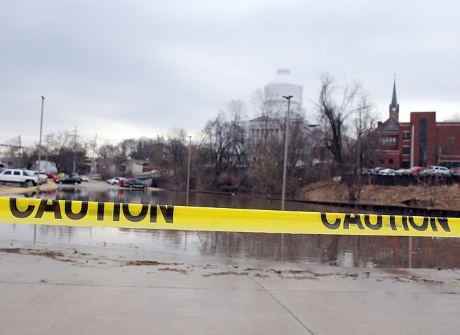 Caution tape warns of high water flooding Thursday in a parking area near the Missouri Capitol.
