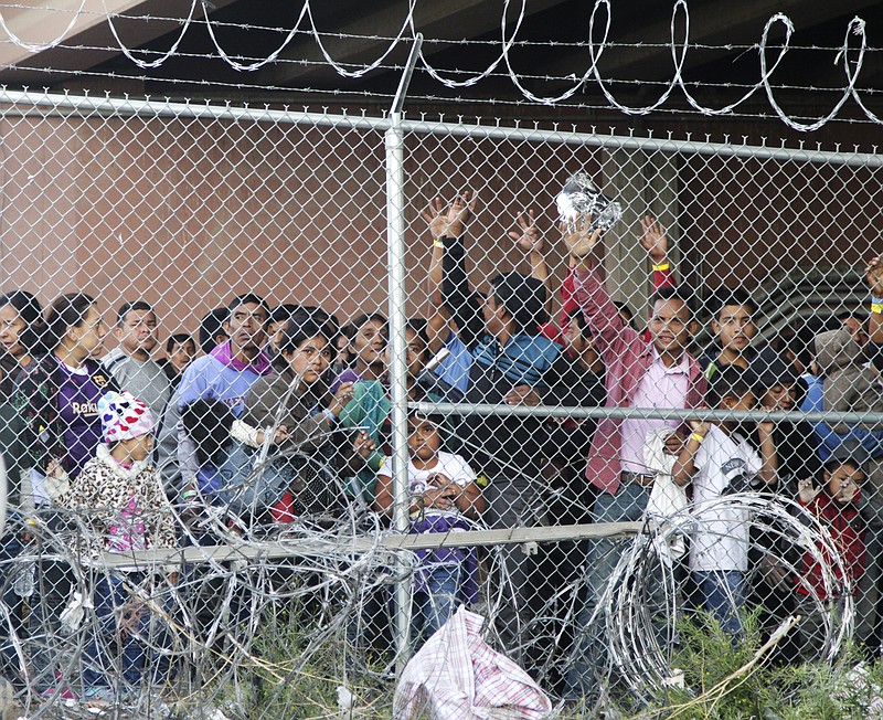 Central American migrants wait for food in El Paso, Texas, Wednesday, March 27, 2019, in a pen erected by U.S. Customs and Border Protection to process a surge of migrant families and unaccompanied minors. Earlier, Customs and Border Protection Commissioner Kevin McAleenan, center, announced the the Trump administration will temporarily reassign several hundred border inspectors, during a news conference at the border in El Paso. (AP Photo/Cedar Attanasio)