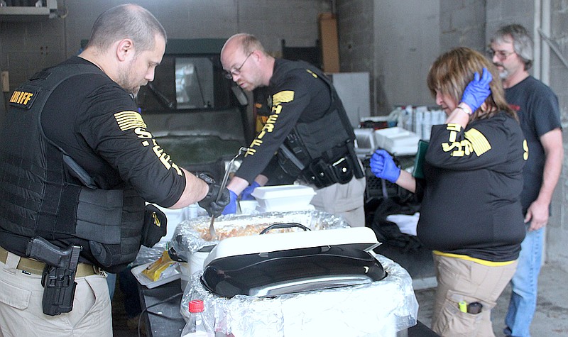 <p>Democrat photo/Liz Morales</p><p>Employees with the Moniteau County Sheriff’s Office work to prepare five meals for Rob Rimel, far right, during the Barbecue Pulled Pork Meal fundraiser March 29 at the Sheriff’s Office.</p>