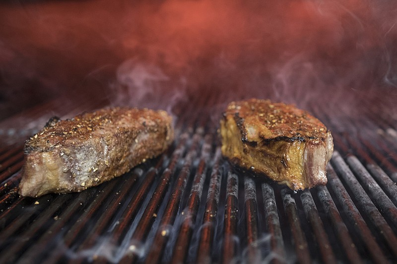 FILE - This Nov. 27, 2018 file photo shows steaks on a grill at a restaurant in New York. The idea behind the low-carb diet is that the body enters a ketogenic, fat-burning state when it runs out of the blood sugar that’s fueled by carbs. Still, many nutrition experts say sticking to a low-carb diet is hard, and not everyone is convinced it should be added to the dietary guidelines. (AP Photo/Mary Altaffer)