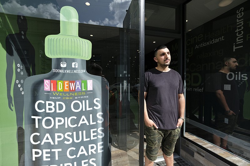 In this photo taken Thursday, March 21, 2019, Gus Dabais stands outside his Sidewalk Wellness store in San Francisco. CBD oil-infused food, drinks and dietary supplements are popular even though the U.S. government says they're illegal and some local authorities have forced retailers to pull products. The confusion has California, Texas and other states moving to legalize the cannabis compound that many see as beneficial to their health. (AP Photo/Eric Risberg)