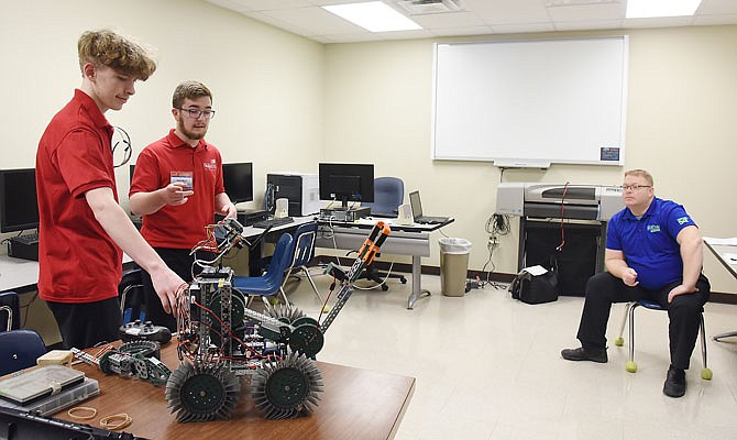 Matt Johnson, seated at right, listens as Nichols Career Center students Elijah Hodgen, left, and Dennis Harris tell the details of how they built the robot on the table. They competed in the Robotics: Urban Search and Rescue portion of this week's SkillsUSA competition at State Tech in Linn.