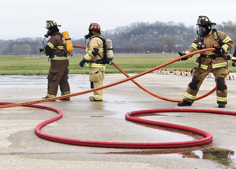 Jefferson City fire and emergency personnel gather the water hose before they put out simulated airplane fire on Saturday, April 6, 2019, at Jefferson City Memorial Airport. Using a simulator that resembles an airplane, crews of three were able to practice putting out the fires throughout the day.