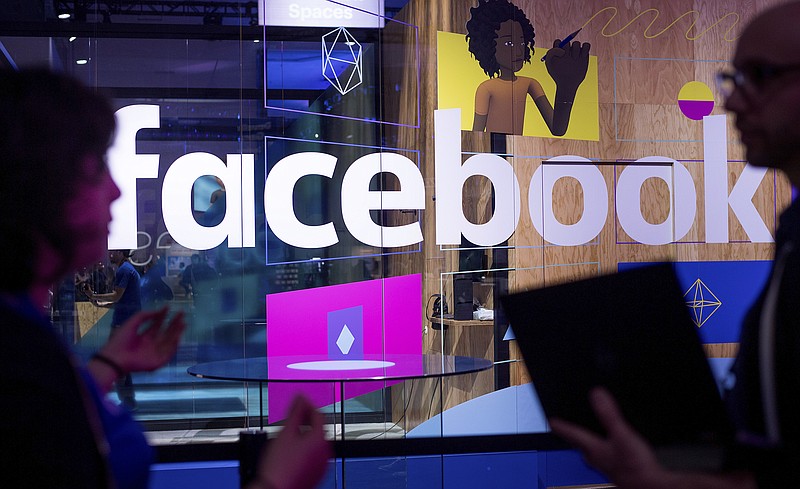 FILE - In this April 18, 2017 file photo, conference workers speak in front of a demo booth at Facebook's annual F8 developer conference, in San Jose, Calif. The U.K. for the first time on Monday April 8, 2019, proposed direct regulation of social media companies, with senior executives potentially facing fines if they fail to block damaging content such as terrorist propaganda or images of child abuse. (AP Photo/Noah Berger, File)