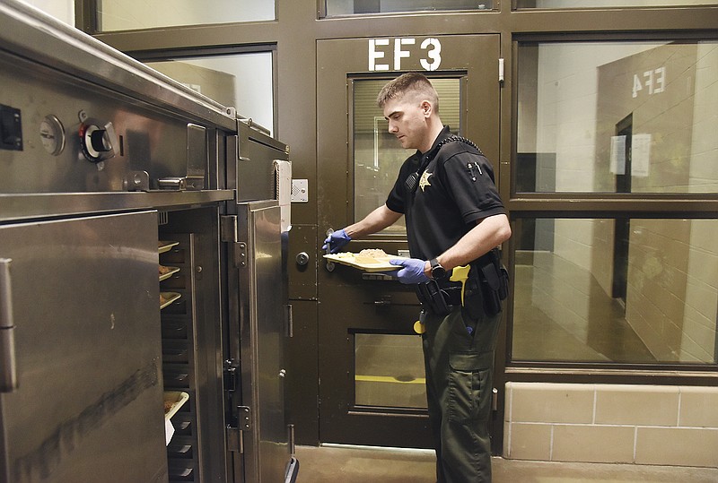 In this April 10, 2019, photo, Cole County Sheriff Deputy Luke Kliegel prepares to serve lunch to inmates in the county jail. Several procedures are put into place for inmate security as well as the safety of the officer serving the trays of food.