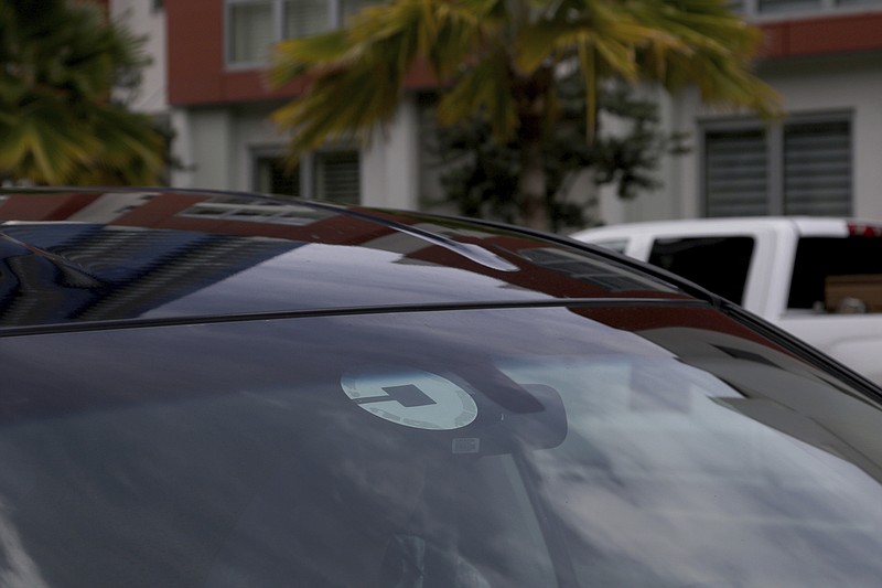 FILE- In this June 6, 2018, file photo Uber driver Joshua Oh drives in Honolulu. Uber launched a voucher program Tuesday, April 9, 2019, enabling companies like Westfield Mall and TGI Fridays to offer free or discounted Uber rides to customers. (AP Photo/Caleb Jones, File)