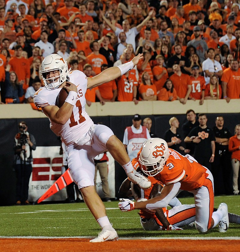 In this Oct. 27, 2018, file photo, Texas quarterback Sam Ehlinger (11) scores a touchdown after escaping from Oklahoma State safety Kenneth Edison-McGruder in the first half of an NCAA college football game, in Stillwater, Okla. Texas has a rising star in quarterback Sam Ehlinger who will get some attention for the Heisman Trophy if he can duplicate his impressive 2018 season when he passed for 25 touchdowns and ran for 16 more. (AP Photo/Brody Schmidt, File)