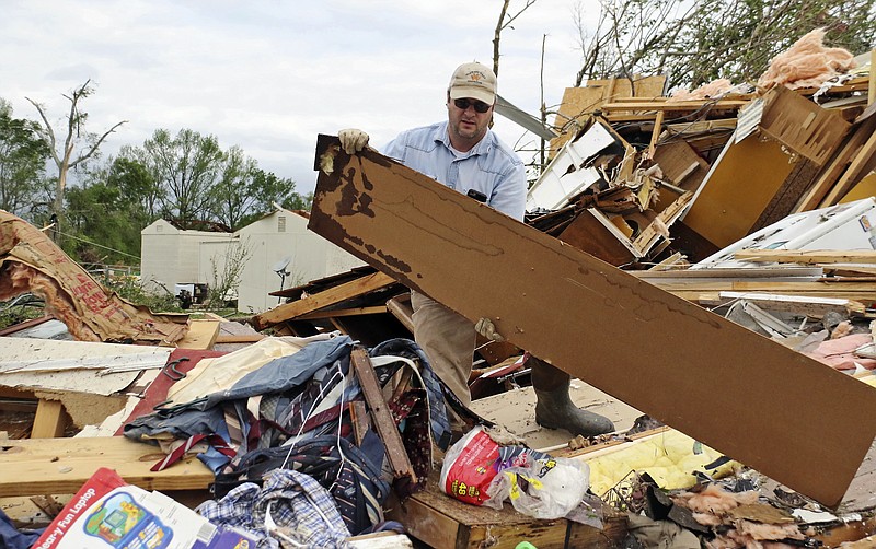 Roman Brown moves part of a wall out of his way as he looks for a friends medicine in their destroyed home along Seely Drive outside of Hamilton, Miss. after a storm moved through the area on Sunday, April 14, 2019. (AP Photo/Jim Lytle)