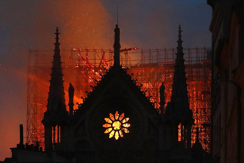 Flames and smoke rise from Notre Dame cathedral as it burns in Paris, Monday, April 15, 2019. Massive plumes of yellow brown smoke is filling the air above Notre Dame Cathedral and ash is falling on tourists and others around the island that marks the center of Paris. 