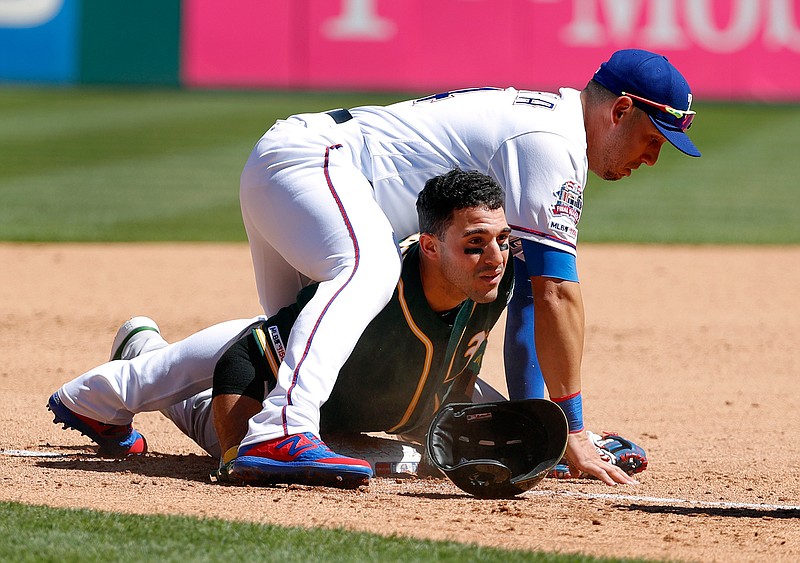  Texas Rangers third baseman Asdrubal Cabrera lands atop Oakland Athletics' Ramon Laureano, who advanced to the bag on a Josh Phegley run-scoring single, in the fourth inning Sunday in Arlington, Texas.  Athletics' Jurickson Profar scored on the play. 