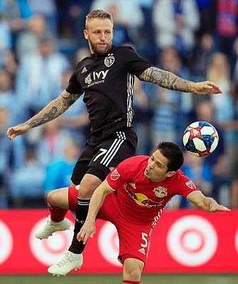 Johnny Russell of Sporting Kansas City plays the ball above New York Red Bulls defender Connor Lade during the first half of Sunday night's MLS match in Kansas City, Kan.