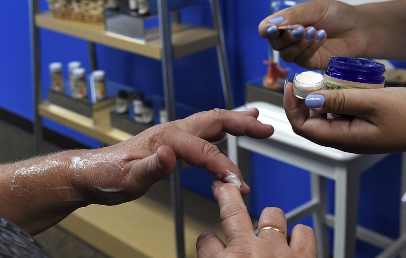FILE - In this Aug. 29, 2018, file photo, a customer tries a free sample of a pain cream that contains cannabidiol (CBD) for her arthritis at Minnesota Hempdropz in Maplewood, Minn. Mainstream retailers are leaping into the world of products like skin creams and oils that tout such benefits as reducing anxiety and helping you sleep. The key ingredient is CBD, or cannabidiol, a compound derived from hemp and marijuana that doesn’t cause a high. (Jean Pieri/Pioneer Press via AP, File)