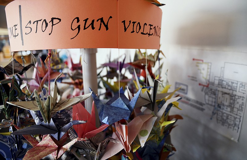 FILE - In this March 23, 2019, file photo, origami cranes, a symbol of peace, hang in the Columbine High School library in Littleton, Colo., near where several survivors and family members of the victims gathered to speak about the upcoming 20th anniversary of the April 20, 1999, shooting. In the two decades since the Columbine High School massacre, therapists still struggle with how to help people cope. (AP Photo/Thomas Peipert, File)