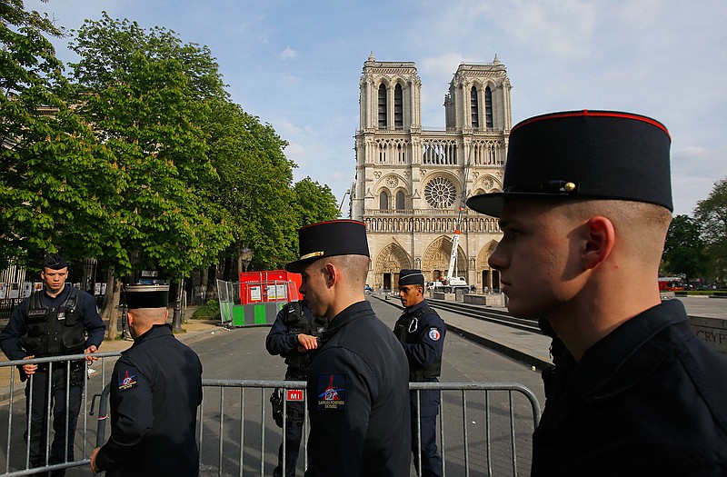Members of Paris Firefighters' brigade enter the security perimeter to Notre Dame cathedral Thursday, April 18, 2019 in Paris. France paid a daylong tribute Thursday to the Paris firefighters who saved Notre Dame Cathedral from collapse, while construction workers rushed to secure an area above one of the church's famed rose-shaped windows and other vulnerable sections of the fire-damaged landmark. (AP Photo/Michel Euler, Pool)