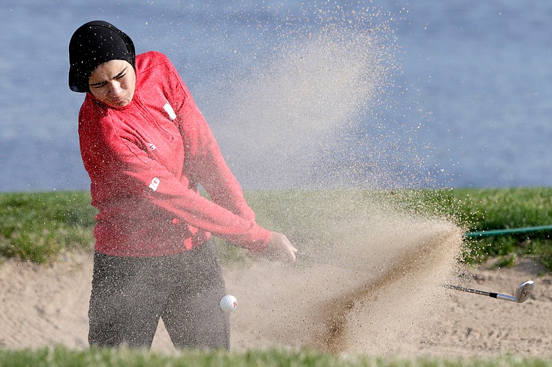 In this April 10, 2019 photo, Noor Ahmed, a member of the Nebraska NCAA college golf team, hits out of a sand trap during practice in Lincoln, Neb. Ahmed is the only golfer at the college level or higher known to wear a hijab while competing. She hopes Muslim girls are watching her and encouraged to chase their dreams in environments where they might encounter fear, uncertainty and hostility. (AP Photo/Nati Harnik)