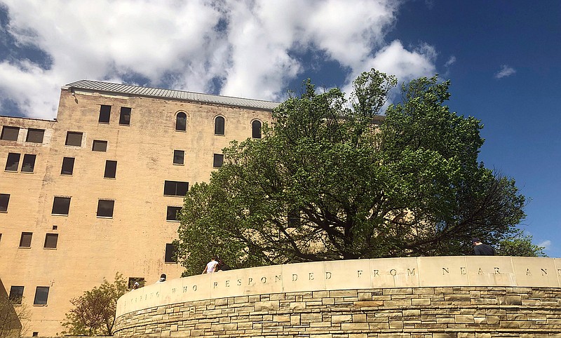 Visitors to the Oklahoma City National Memorial walk around the "Survivor Tree," a 100-year-old American elm and symbol of hope after the deadly 1995 bombing, Friday, April 19, 2019, in Oklahoma City. Science and technology are helping Oklahoma City to sustain the DNA of the tree symbolizing hope 24 years after the deadliest act of domestic terrorism on U.S. soil. As part of an annual remembrance of the bombing, civic leaders on Friday plan to transplant a tree that was cloned from the scarred American elm that lived through the blast. They hope the younger elm will replace the "Survivor Tree" once it dies. (AP Photo/Adam Kealoha Causey)