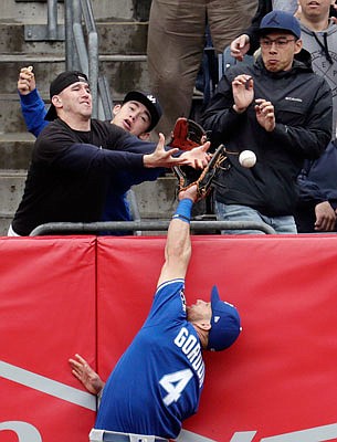 A fan interferes as Royals left fielder Alex Gordon leaps to try to make a catch on a ball hit by Gleyber Torres of the Yankees during the third inning of Saturday's game in New York.